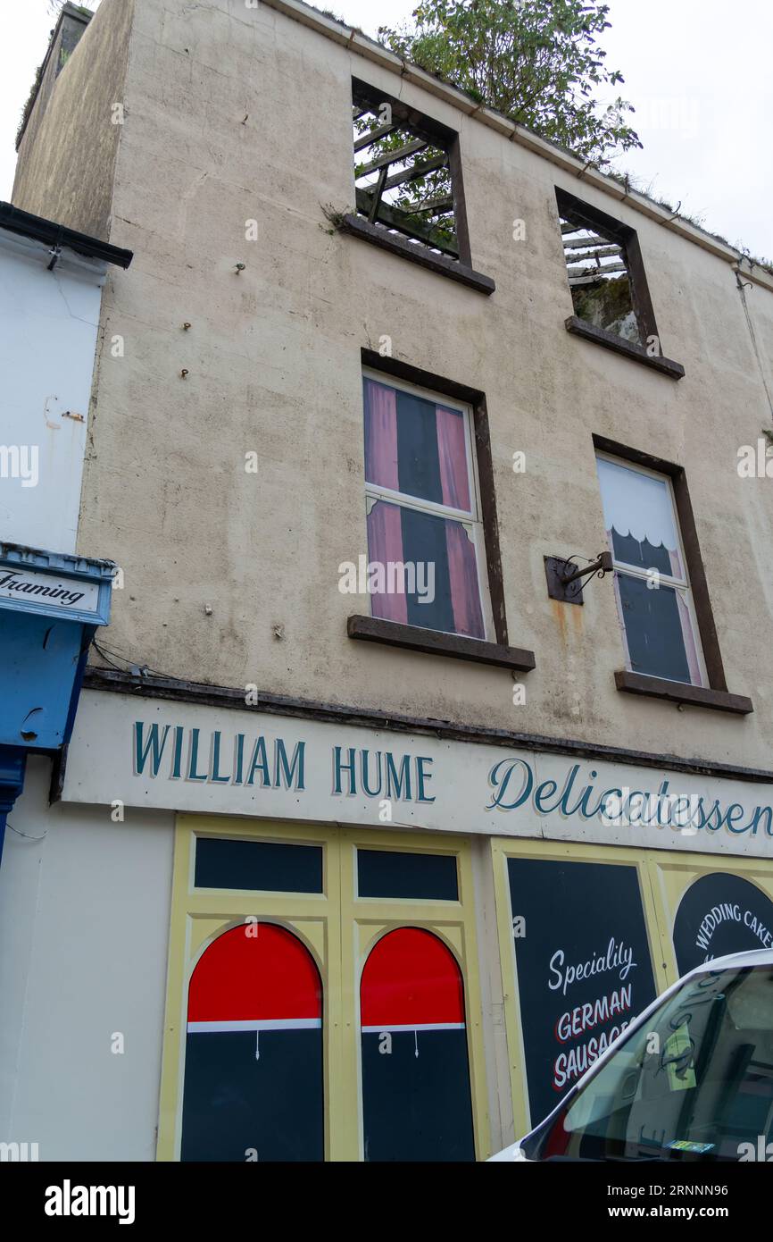 Eine falsche Fassade auf leerstehenden Grundstücken mit dem fehlenden Dach durch die Fenster im obersten Stockwerk. Konzept leerer Geschäfte, Sparmaßnahmen, Niedergang der Hauptstraße Stockfoto