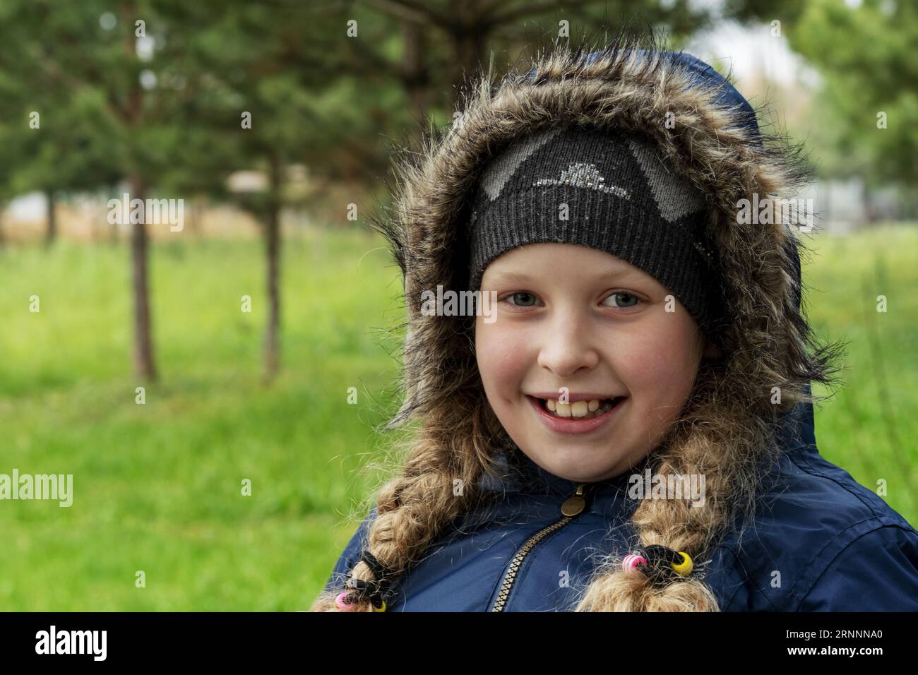 Ein Teenager in einer warmen Jacke. Warm gekleidetes Mädchen mit Hut und Zöpfen. Porträt eines schönen Mädchens im Spätherbst, frühen Frühling Stockfoto