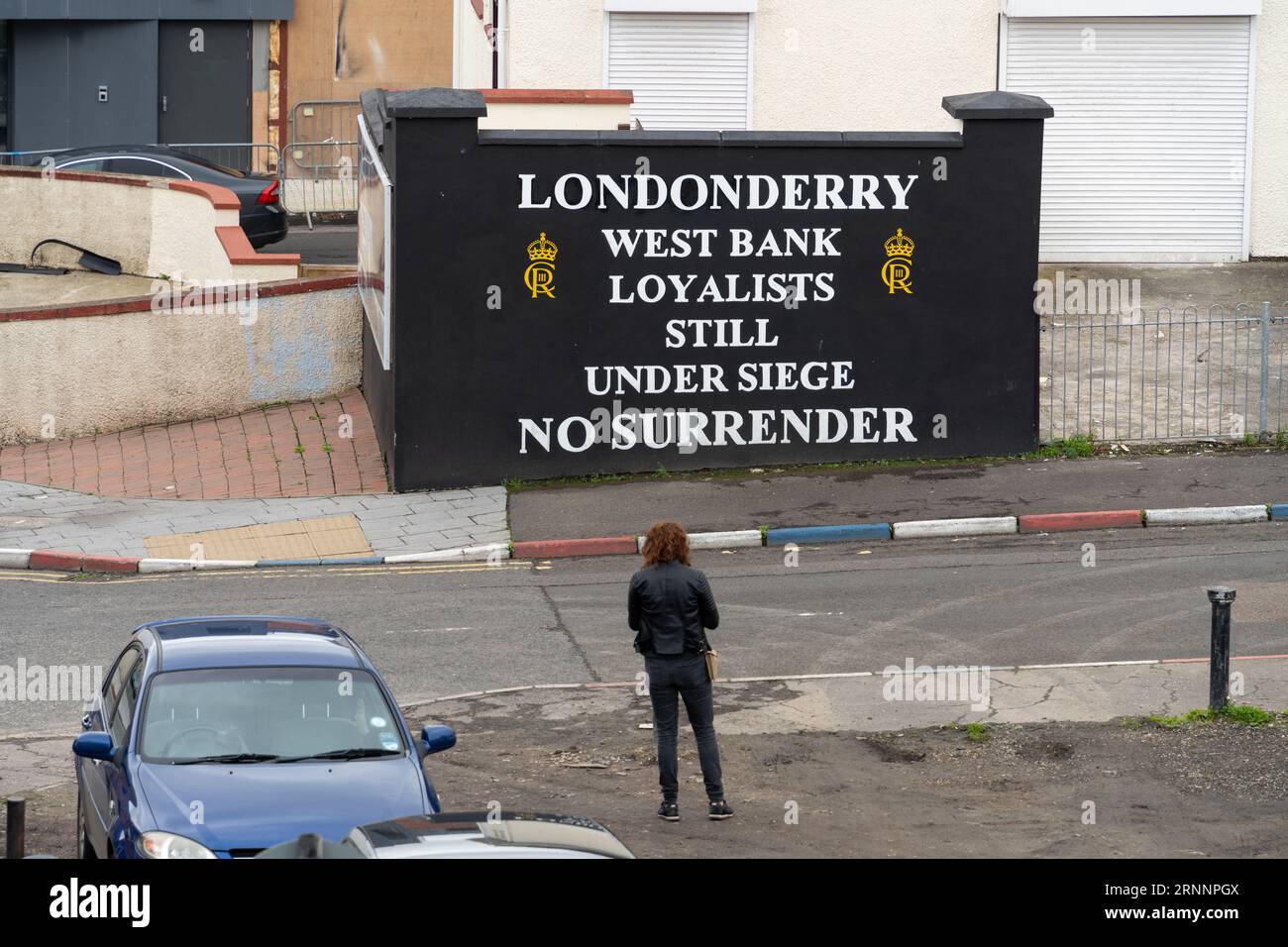 Ein Besucher steht an einem loyalistischen Schild in Derry-Londonderry, Nordirland Stockfoto