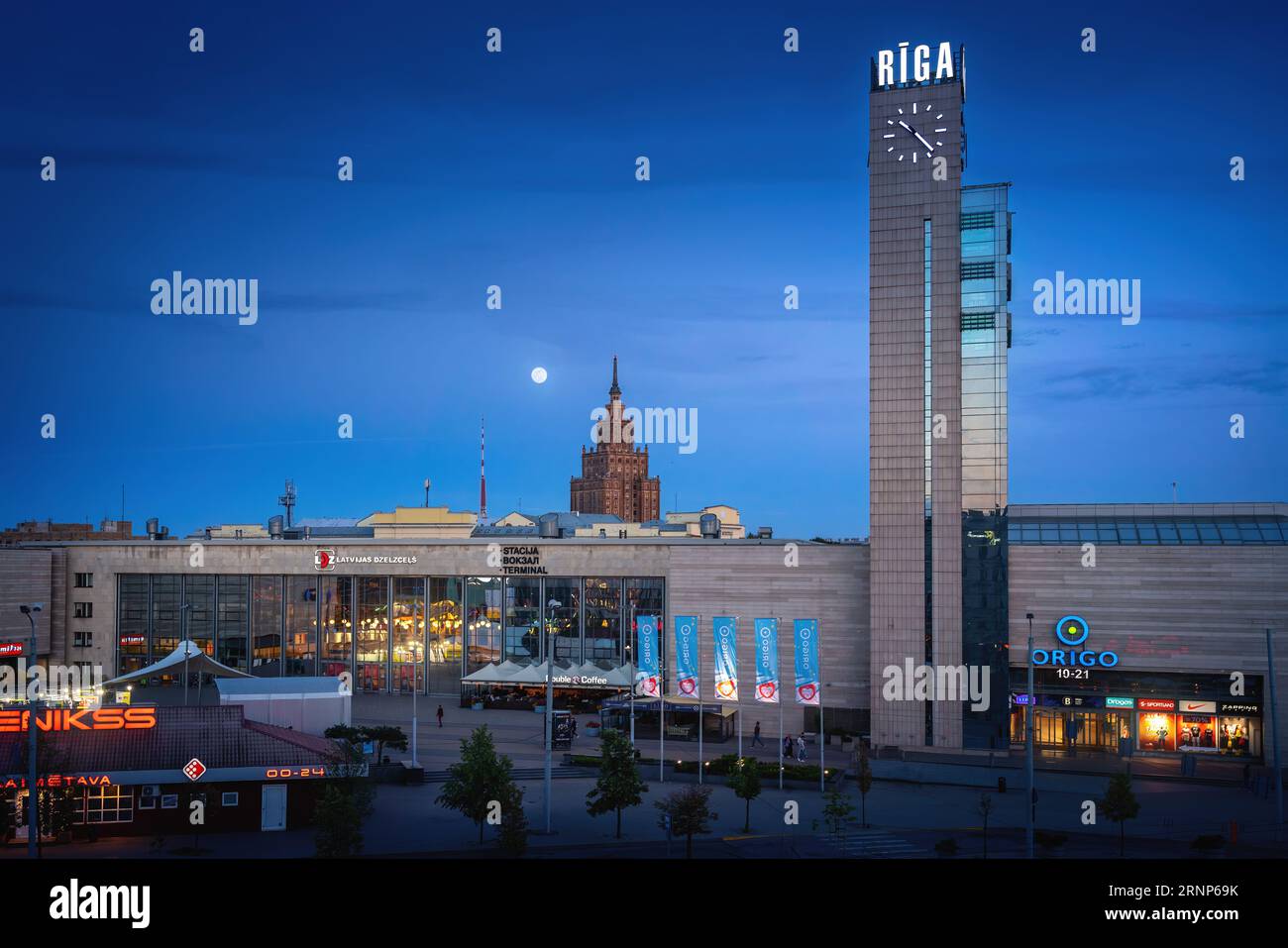 Uhrturm des Hauptbahnhofs und Lettische Akademie der Wissenschaften bei Nacht - Riga, Lettland Stockfoto