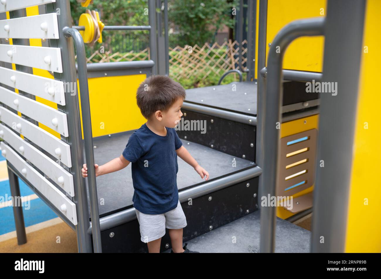Ein niedlicher, zweijähriger Junge genießt einen Sommertag mit Spaß beim Erkunden von Spielzeugen im Park Stockfoto