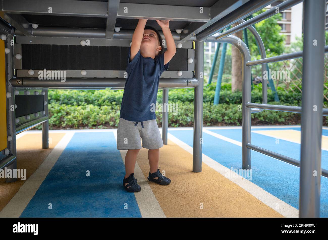 Ein niedlicher, zweijähriger Junge genießt einen Sommertag mit Spaß beim Erkunden von Spielzeugen im Park Stockfoto