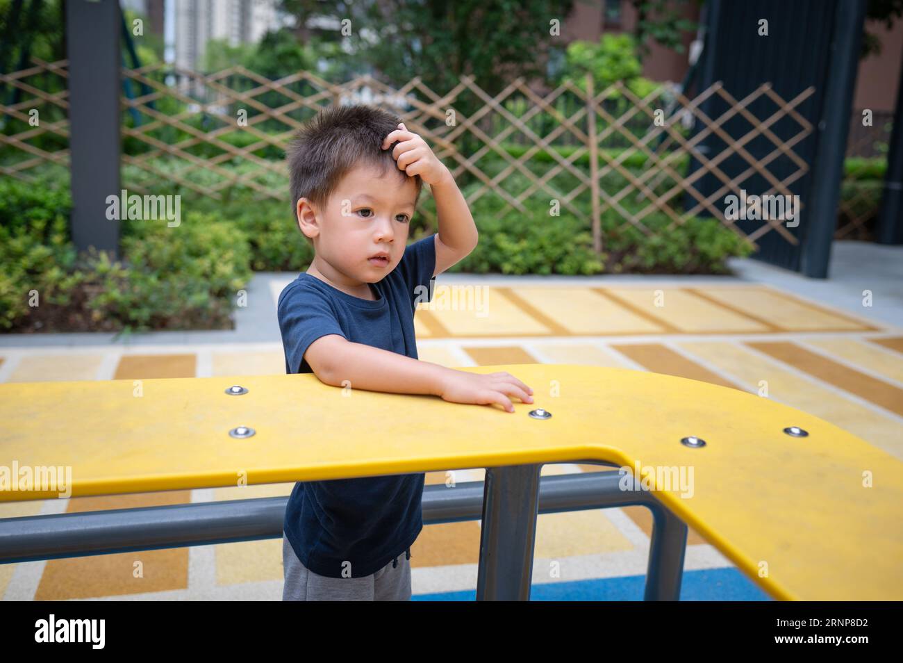Ein niedlicher, zweijähriger Junge genießt einen Sommertag mit Spaß beim Erkunden von Spielzeugen im Park Stockfoto