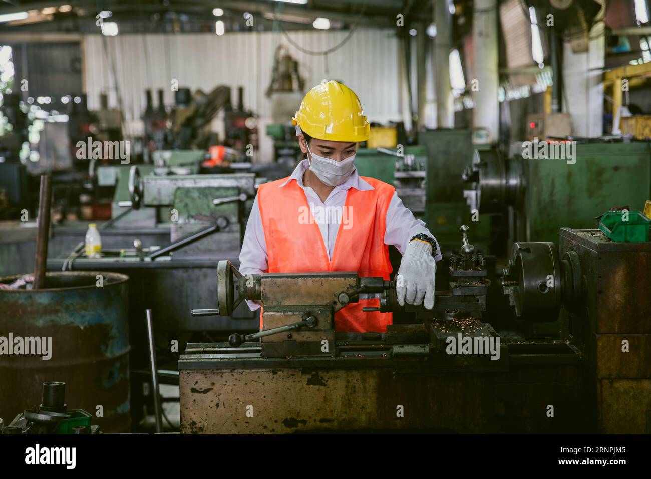 Asiatische Arbeitnehmerin, die in der Schwermetallindustrie arbeitet, trägt Gesichtsmaske für Hygiene, gesunde Sicherheit Stockfoto