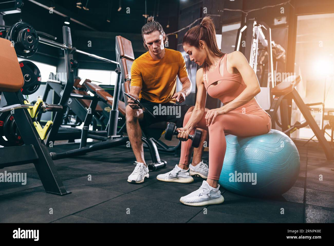 Sport-Frau trainiert Muskeln in der privaten Klasse Fitnessstudio mit Personal Trainer helfen Unterstützung Stockfoto