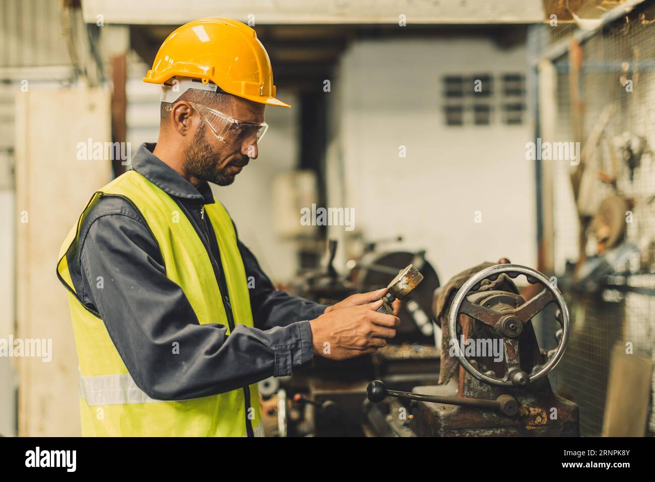 Hispanischer lateinischer indischer professioneller Techniker, der mit einer Präzisionsfräsmaschine aus Stahl in einer Drehmetallfabrik arbeitet Stockfoto