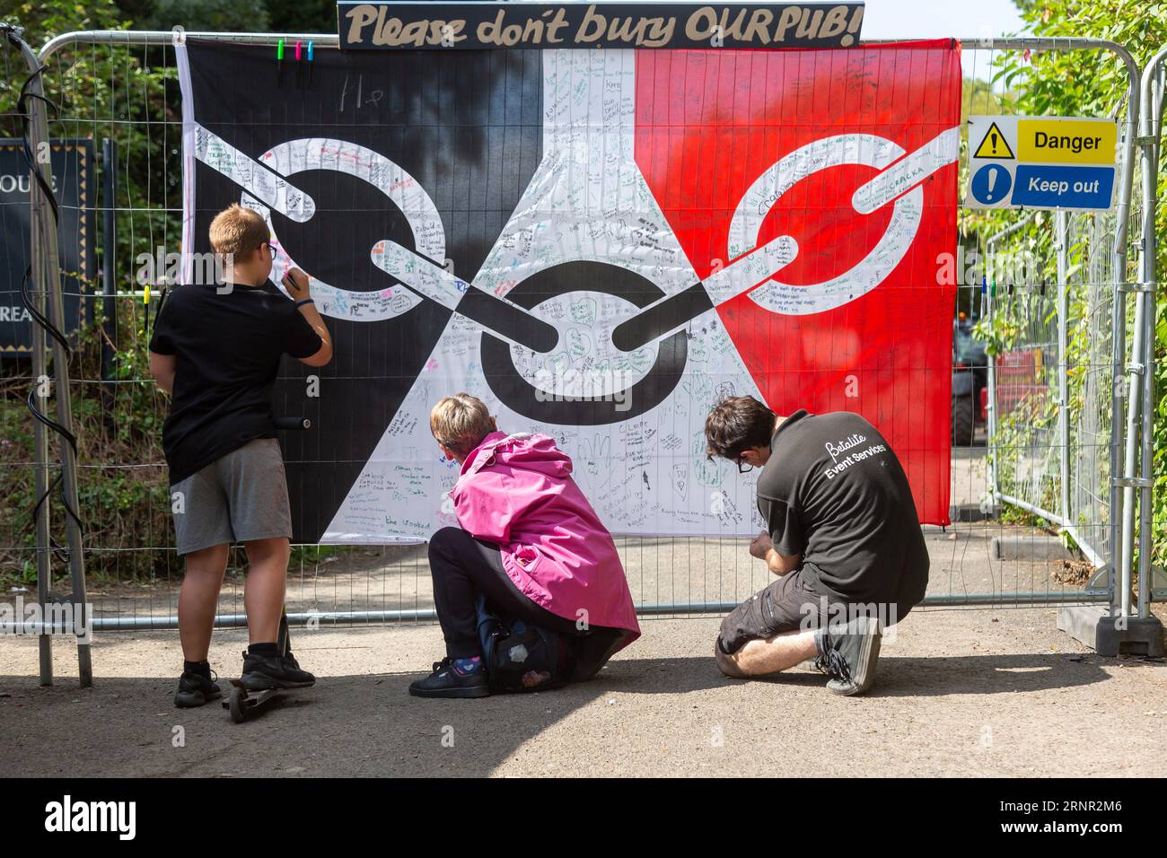 Himley, Staffordshire, Großbritannien. September 2023. Vier Wochen nach dem Abbrennen des berühmten Crooked House Pub werden Protestschilder und die Flagge des Schwarzen Landes angebracht, um den Wiederaufbau des Grundstücksgebäudes an derselben Stelle zu unterstützen. Die Flagge des Schwarzen Landes wird unterzeichnet und mit Unterstützungsbotschaften versehen. Von Einheimischen. Die Aktivisten sagen, dass sie dort sein werden, bis sie wissen, dass der Pub wieder aufgebaut wird. Quelle: Peter Lopeman/Alamy Live News Stockfoto