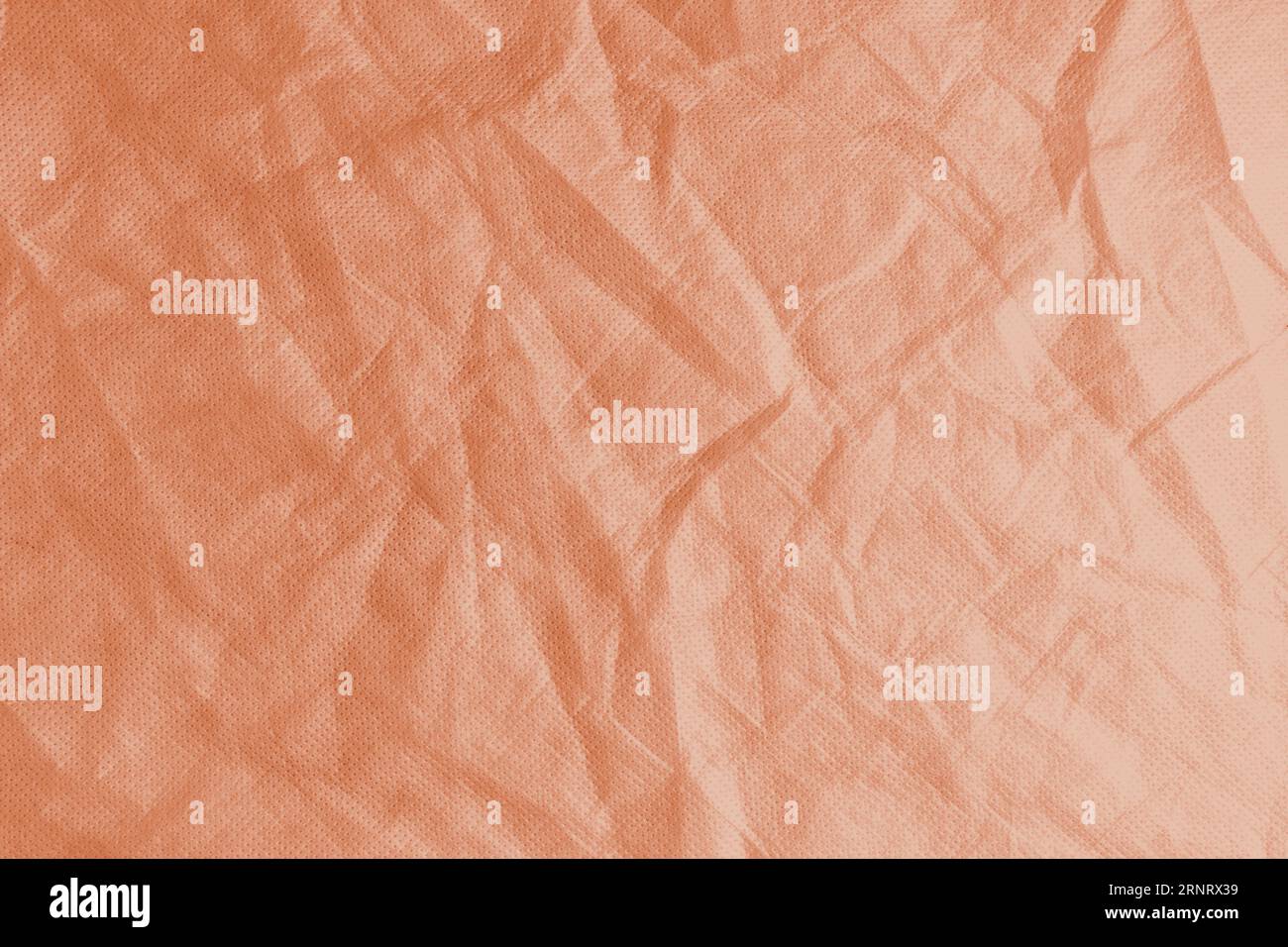 Zerknitterter, zerknitterter orangefarbener Texturhintergrund. Zerknitterte und geknitterte abstrakte Kulisse aus Spinnvlies, Tapete mit Kopierraum, Draufsicht. Stockfoto