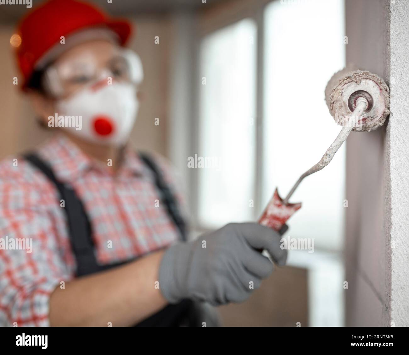 Bauarbeiterin mit Helmmalerwalze Stockfoto