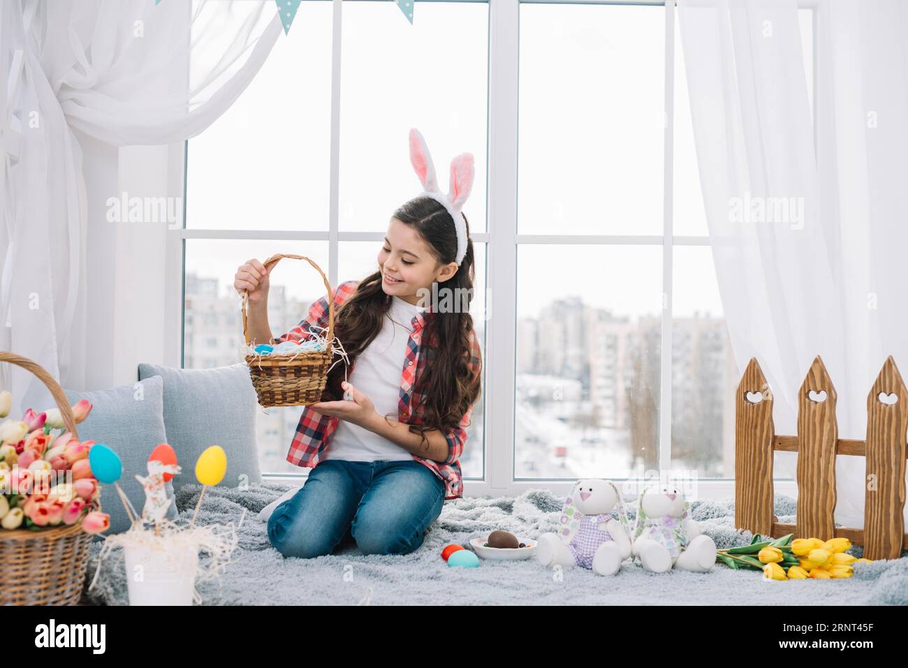 Mädchen, das im Bett sitzt und ostereierkorb nach Hause schaut Stockfoto