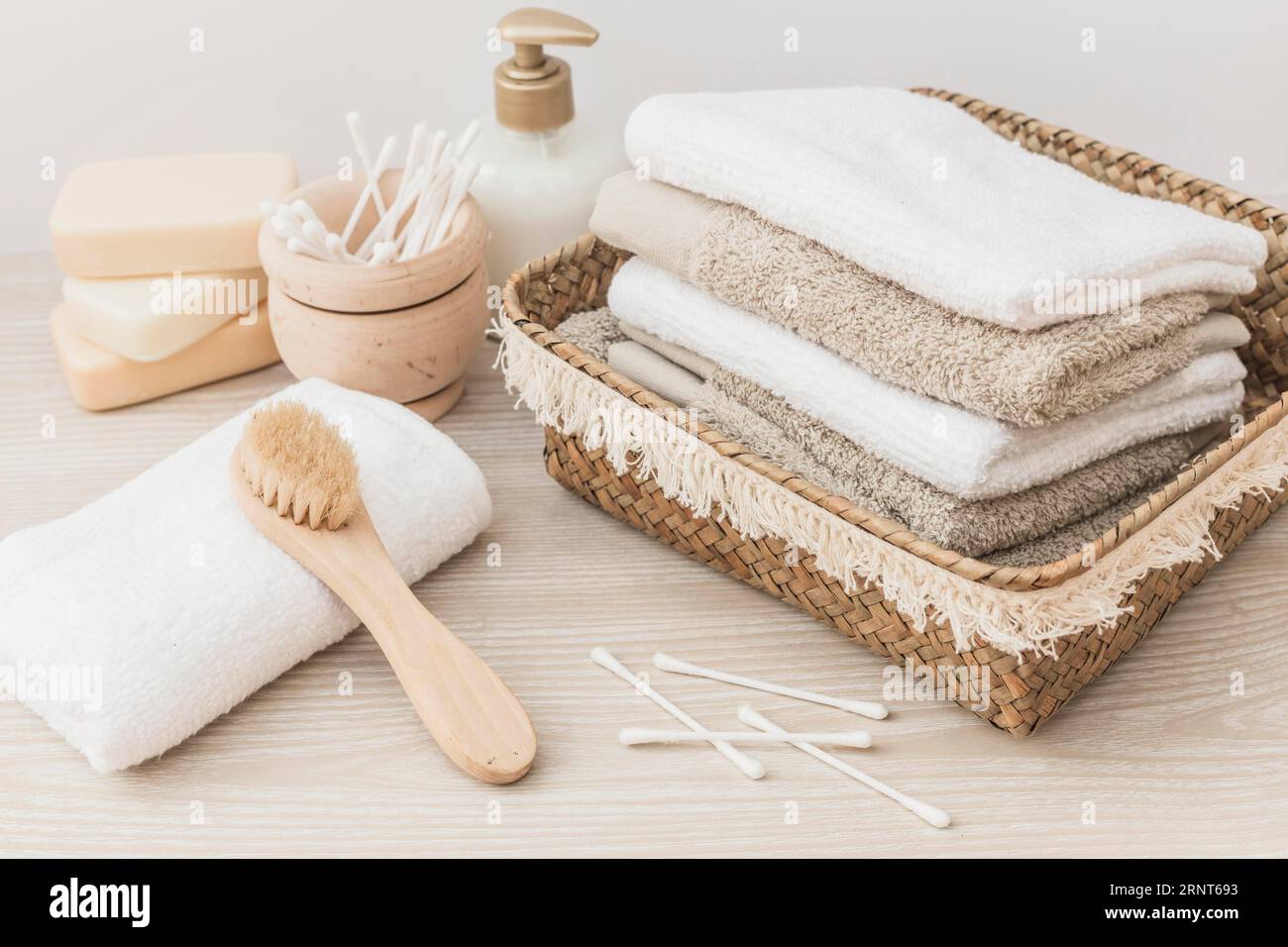 Gestapelte Handtücher Bürstenseife Baumwolltupfer Kosmetikflasche hölzerner Hintergrund Stockfoto