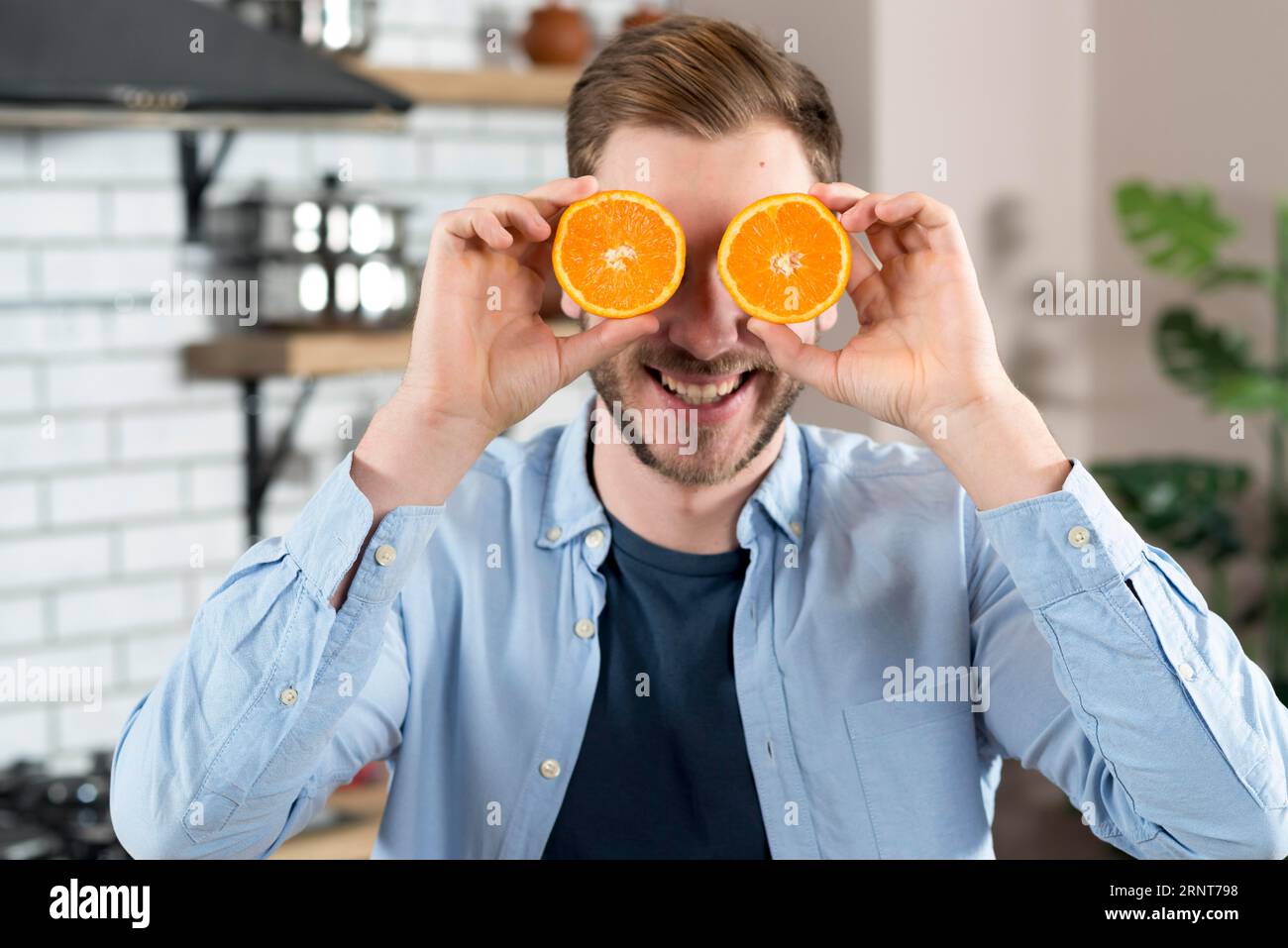 Junger Mann macht Spaß mit zwei Orangen schneiden nach Hause Stockfoto