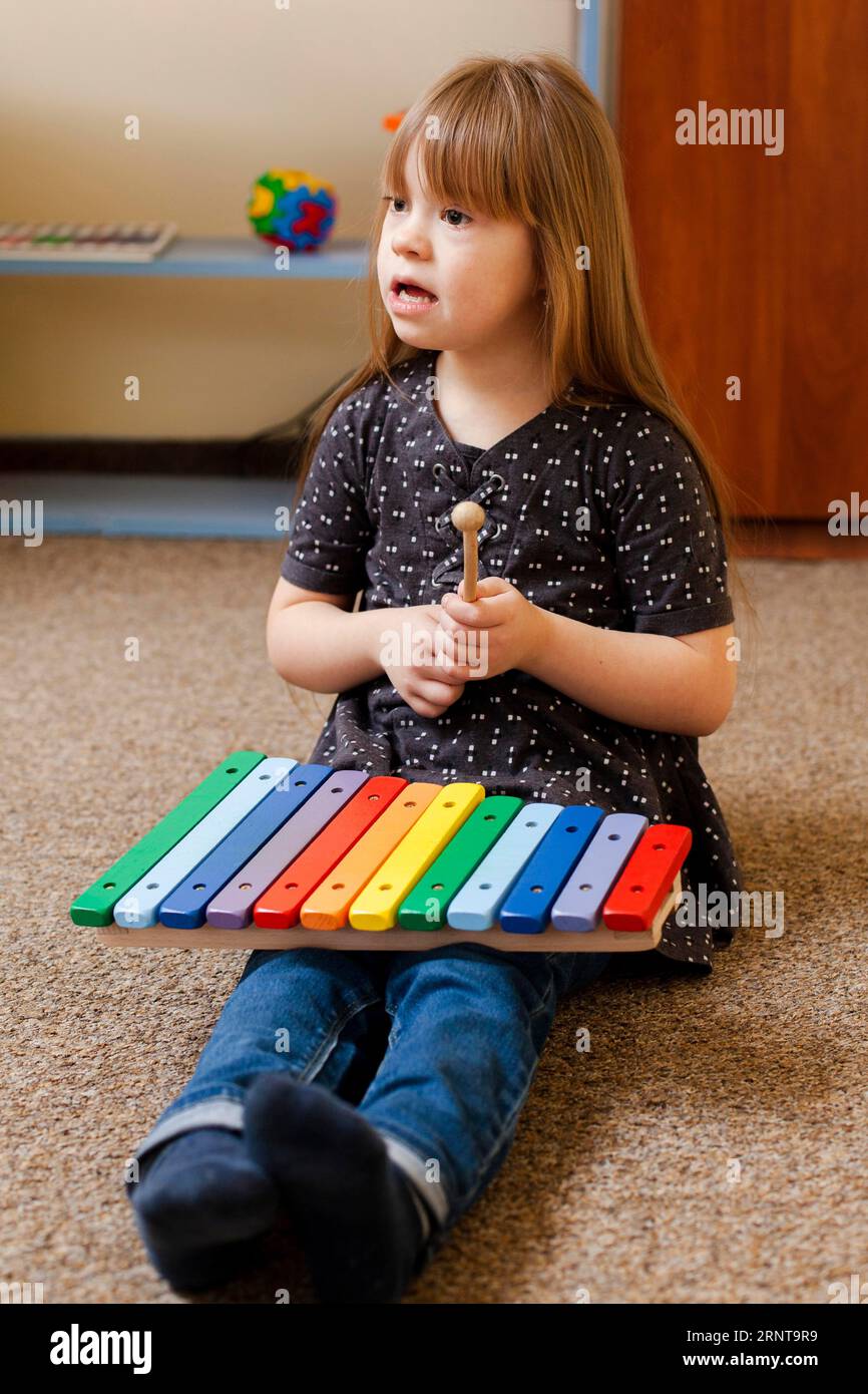 Mädchen mit Down-Syndrom spielt mit buntem Xylophon Stockfoto