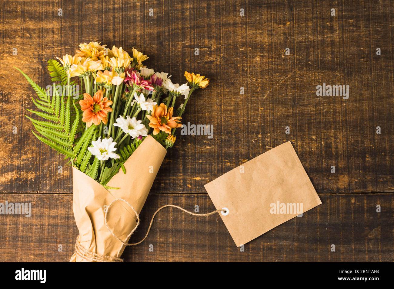 Deckenansicht zarte Blumenbüschel braunes Papieretikett mit Holzoberfläche Stockfoto