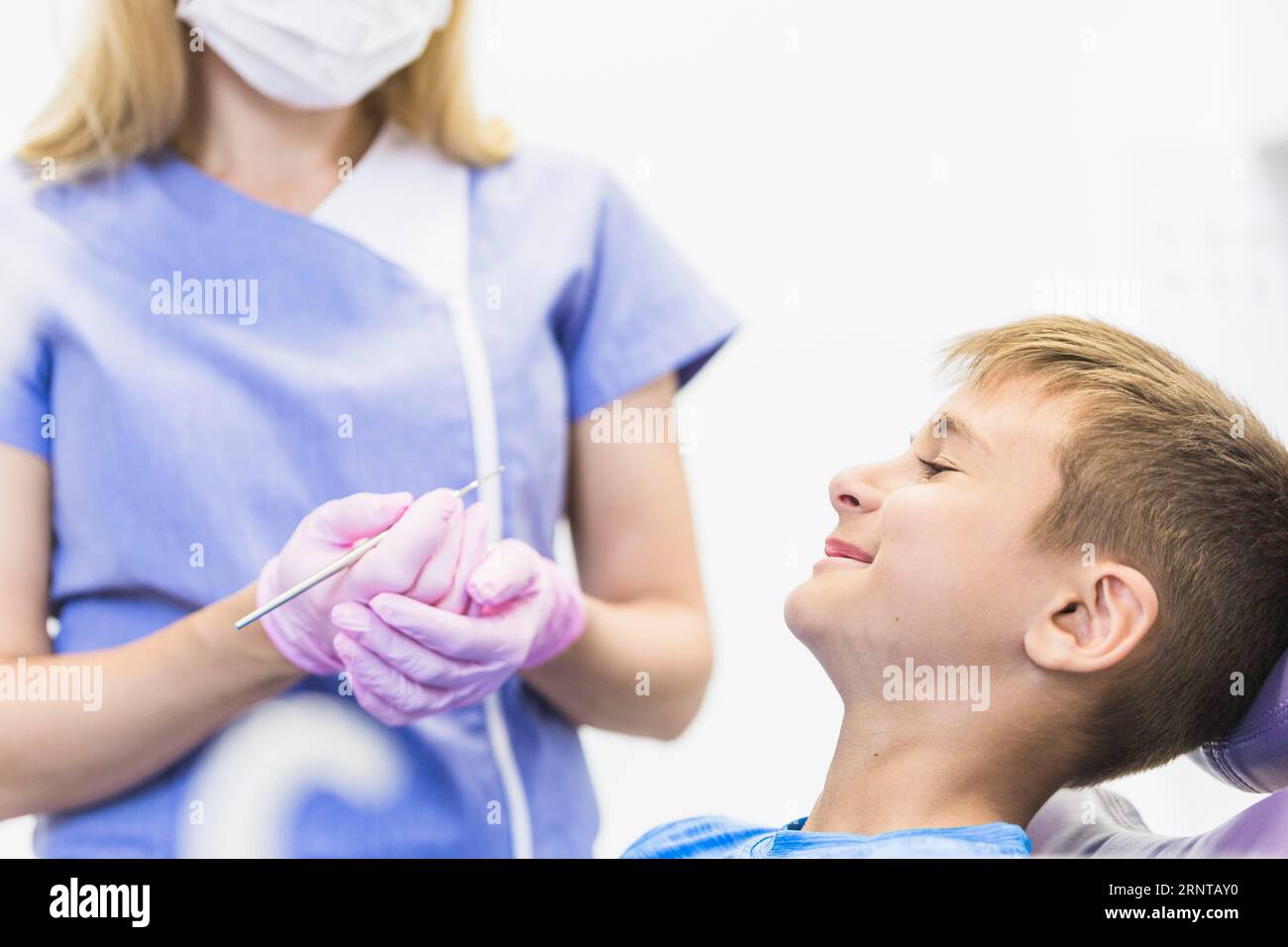 Lächelnde Kinderpatientenfront Zahnärztin mit Skaler Stockfoto