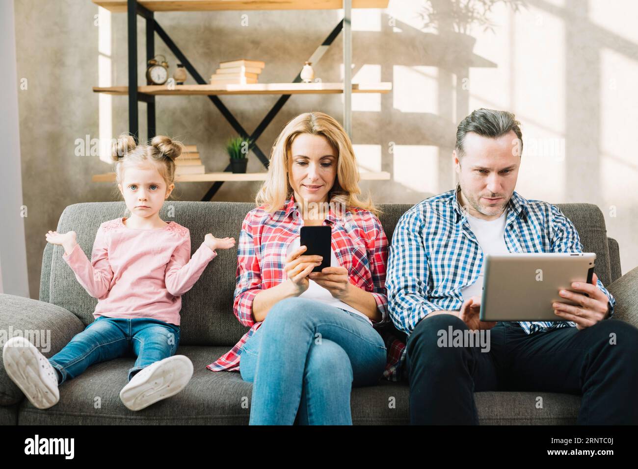 Wütende Tochter sitzt auf dem Sofa mit ihrem Vater und nutzt ein digitales Tablet-Handy zu Hause Stockfoto