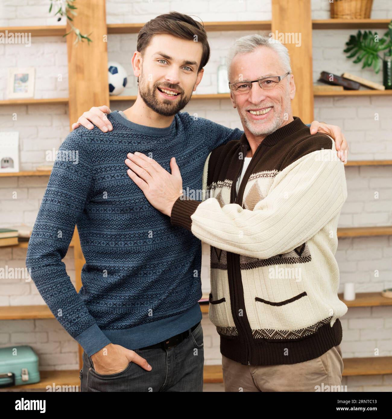 Ein alter glücklicher Mann, der sich mit einem jungen, lächelnden Mann umarmt Stockfoto
