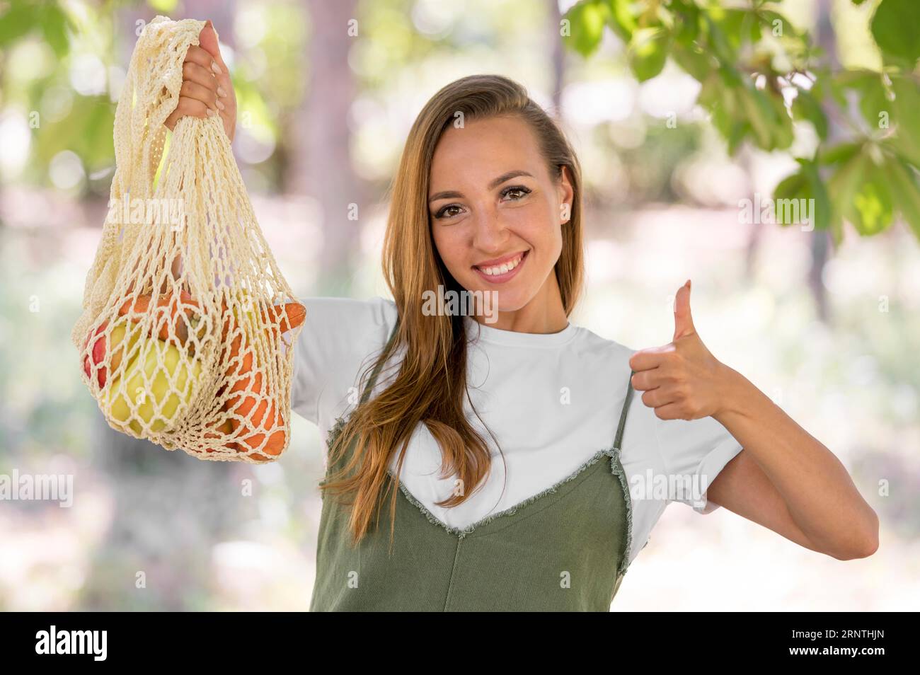 Eine Frau, die mit Daumen nach oben zeigt, dass sie eine biologisch abbaubare Tasche mit Leckereien hat Stockfoto