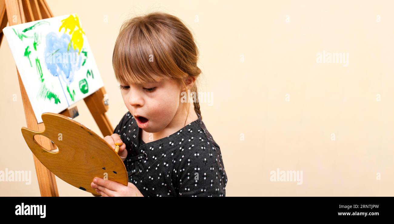 Mädchen mit Down-Syndrom mit Palettenmalerei Stockfoto