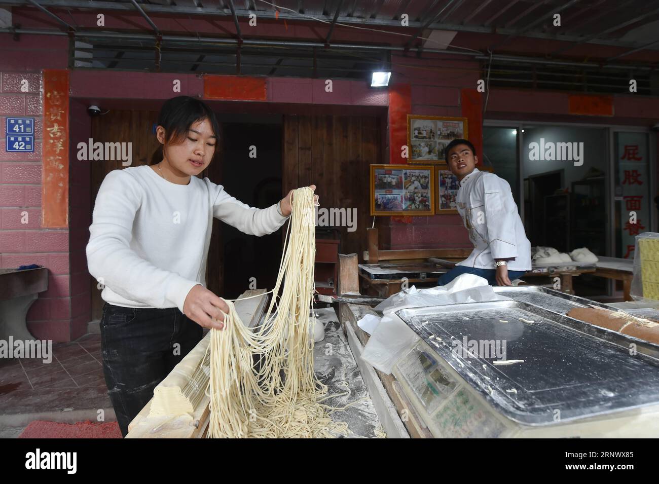 (180104) -- NAN, 4. Januar 2018 -- Guo Weilan (L) macht Nudeln im Dorf Pendao der Gemeinde Penghua in der Stadt Nan, südöstliche chinesische Provinz Fujian, 3. Januar 2018. Um sich um die Eltern zu kümmern, kam der 23-jährige Guo Weilan nach seinem Abschluss nach Hause und verkaufte Nudeln. Der Nudelladen, der eine hundertjährige Geschichte hat, gehört ihren Eltern. Guo ist die vierte Generation, die diesen Nudelladen betreibt. Neben dem Verkauf von Nudeln im Geschäft verkauft sie sie auch im Internet zusammen mit Produkten anderer Dorfbewohner.) (dhf) CHINA-FUJIAN-NUDEL (CN) SongxWeiwei PUBLICATIONxNO Stockfoto