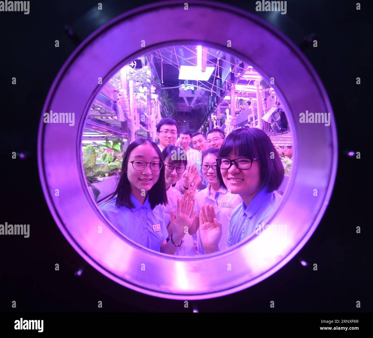 (180128) -- PEKING, 28. Januar 2018 -- Freiwillige der ersten Gruppe und der zweiten Gruppe winken in der Kabine der Beihang-Universität in Peking, 26. Januar 2018. Zwei männliche und zwei weibliche Studenten von der Beihang University, der zweiten Gruppe von Freiwilligen, die in Yuegong-1, auch bekannt als Lunar Palace 1, übernachteten, vollendeten die zweite Phase des 365-tägigen Experiments am Freitag und stellten einen Weltrekord für den längsten Aufenthalt in einer abgeschlossenen Kabine auf. Die erste Gruppe von Freiwilligen, die zuvor 60 Tage in der Kabine verbracht hatte, trat wieder in die Kabine ein, um die zweite Gruppe zu ersetzen, und startete das dritte und letzte Mal Stockfoto