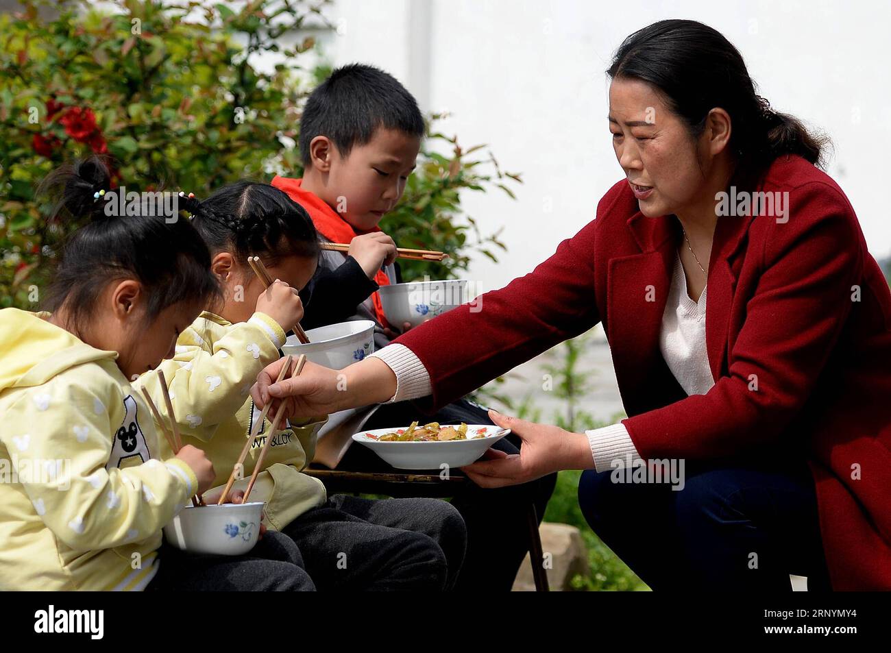 (180327) -- PINGLI, 27. März 2018 -- Schüler essen in der Schule mit Hilfe von Li Zhaoqiong, Ehefrau von YE Shiping, in der Stadt Xihe im Kreis Pingli, Provinz Shaanxi im Nordwesten Chinas, 26. März 2018. YE Shiping, 53 Jahre alt, entschied sich, als Lehrer mit seiner Frau an der Renjiaya Primary School zu bleiben, da die Anzahl der Schüler hier auf nur 15 zurückging. Die Schule liegt in abgelegenen Bergregionen und ist 30 Kilometer vom County entfernt. Mit dem Bevölkerungsrückgang wurden YE und seine Frau die einzigen zwei Lehrer, die noch in der Schule waren. Das Paar hat sich gut um ihre Schüler gekümmert Stockfoto