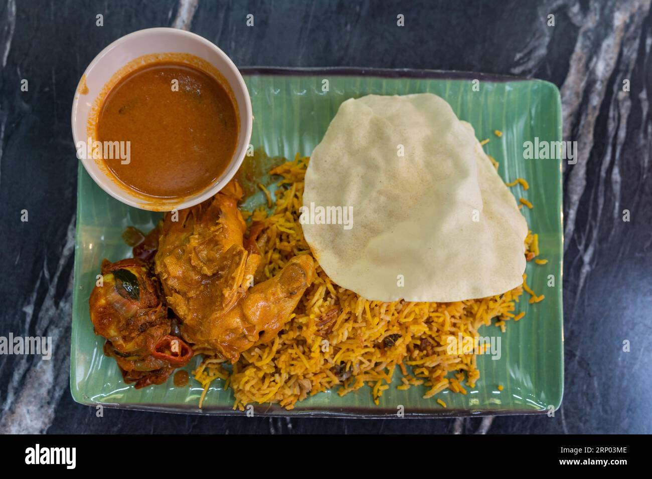 Blick von oben auf den Biryani-Reis mit Curryhähnchen und Papadam Stockfoto