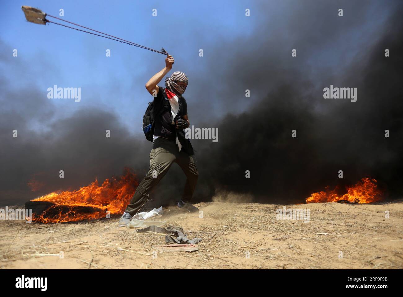 (180511) -- GAZA, 11. Mai 2018 -- Ein palästinensischer Demonstrant schleudert mit einer Schleuder Steine auf israelische Truppen während der Zusammenstöße an der Grenze zwischen Gaza und Israel, östlich des südlichen Gaza-Streifens von Khan Younis, am 11. Mai 2018. Am Freitag brachen an der Ostgrenze des Gazastreifens zu Israel während der Proteste gegen Israel am siebten Freitag Zusammenstöße zwischen palästinensischen Demonstranten und israelischen Soldaten aus, sagten medizinische Quellen. (Zxj) MIDEAST-GAZA-KONFLIKTE YasserxQudih PUBLICATIONxNOTxINxCHN Stockfoto