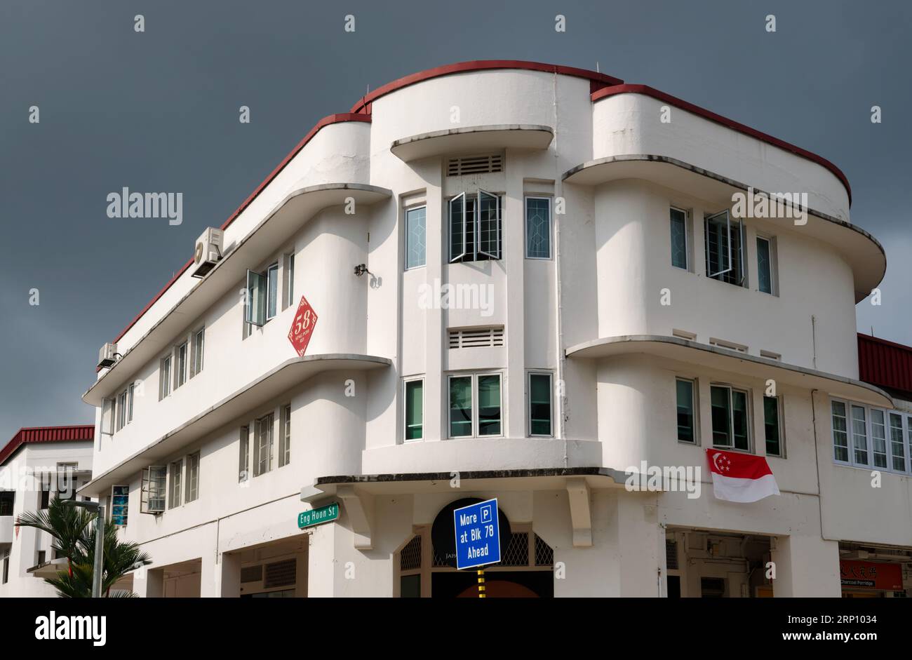 Ein weißes Gebäude im Art déco-Stil in der eng Hoon Street, Tiong Bahru Heritage Area, Singapur, mit dunklen Regenwolken über dem Himmel Stockfoto