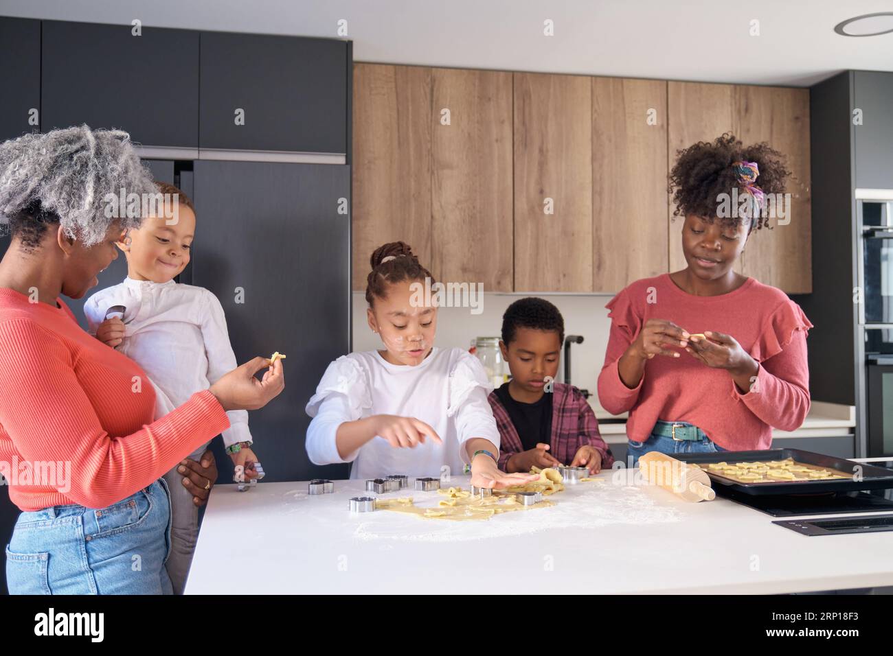 Afrikanische Familie schneidet Keksformen in einem Keksteig in der Küche. Horizontale erweiterte Familie. Stockfoto