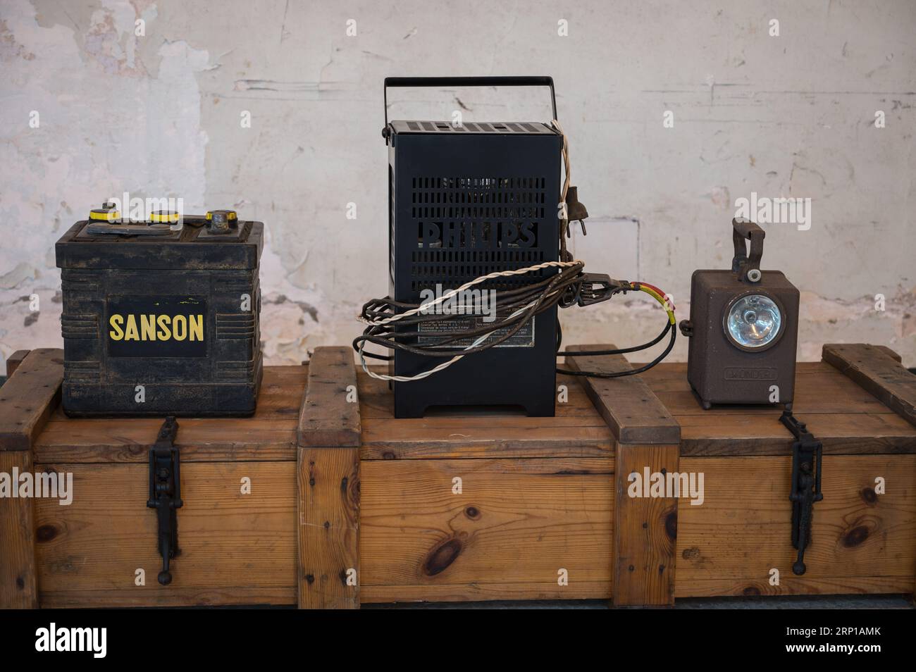 Eine alte Sanson Autobatterie, ein Philips Batterieladegerät und eine Werkstattlampe Stockfoto