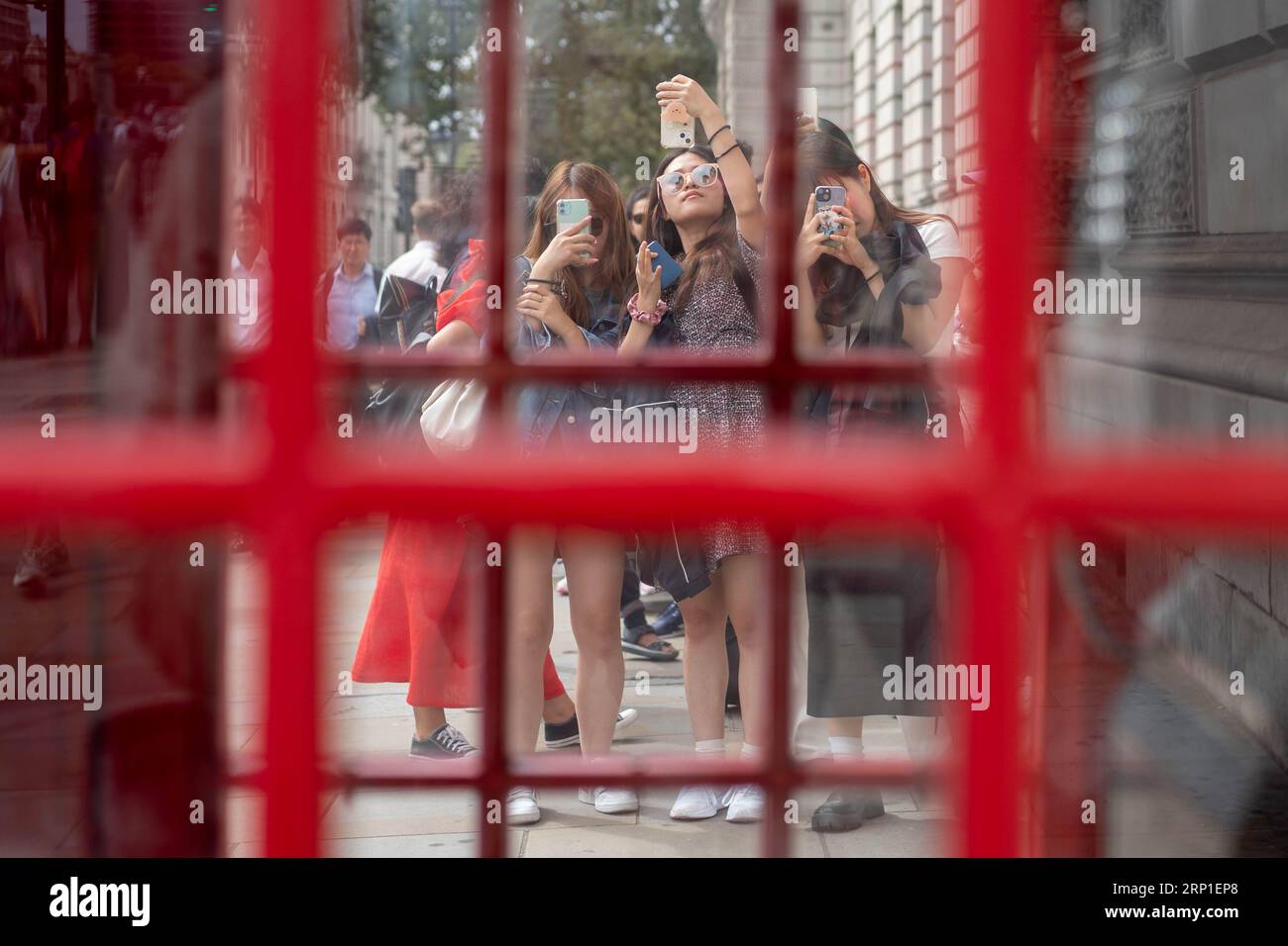 Die Leute fotografieren eine rote Telefonbox am Parliament Square in Westminster, London, während die Popularität der berühmten Kabinen im Zeitalter der sozialen Medien andauert, während sie sich ihrem 100. Jahrestag nähern. Die berühmte rote Telefonbox wurde von dem Architekten Sir Giles Gilbert Scott für einen Wettbewerb im Jahr 1924 entworfen. Bilddatum: Freitag, 11. August 2023. Stockfoto