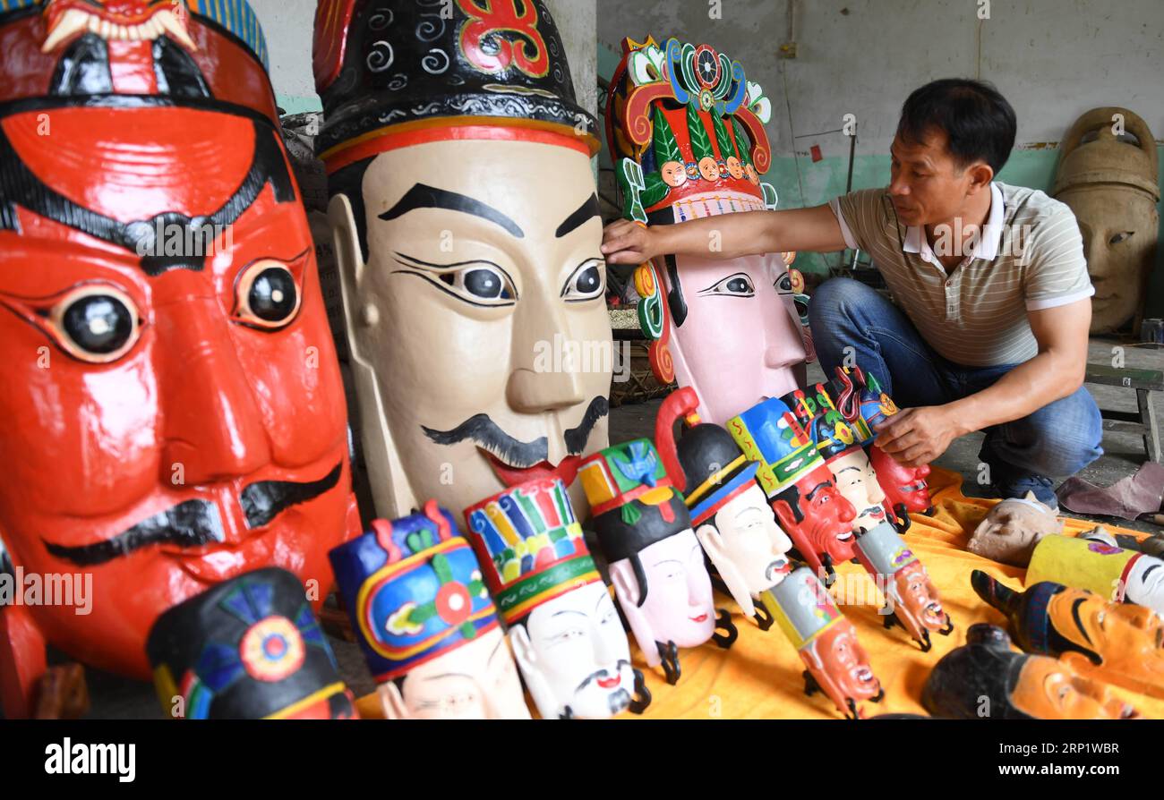 (180726) -- HUANJIANG, 26. Juli 2018 (Xinhua) -- Fang Wenzhan präsentiert die Maonan Nuo Masken, die er in der autonomen Provinz Huanjiang Maonan, der südchinesischen autonomen Region Guangxi Zhuang, am 25. Juli 2018 hergestellt hat. Die Masken bestehen aus vier Kategorien und 72 Arten von Gesichtern, die auf verschiedenen Zeichen basieren. Fang Wenzhan ist der Erbe der Maonan Nuo Mask Making und ein Erbe der Maonan Wood Carving, einer autonomen regionalen Ebene immaterieller kultureller Erbe. (Xinhua/Lu Boan)(GXN) CHINA-GUANGXI-MAONAN ETHNIC GROUP-NUO MASK-INHERITOR (CN) PUBLICATIONxNOTxINxCHN Stockfoto