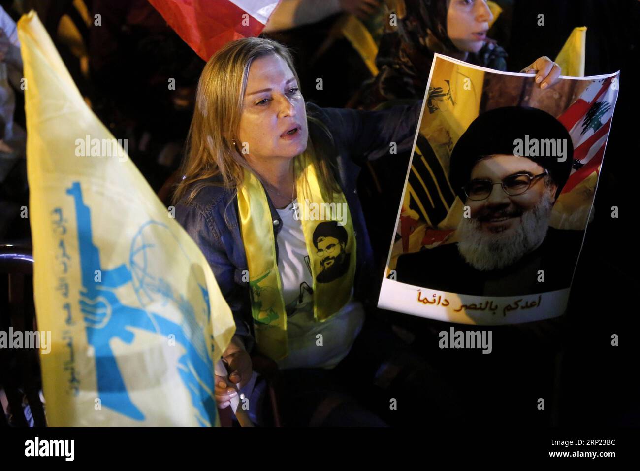 (180815) -- BEIRUT, 15. August 2018 -- Eine Frau hält die Flagge der Hisbollah und das Bild des Hisbollah-Führers Sayyed Hassan Nasrallah während einer Fernsehrede in Beirut, Libanon, 14. August 2018. Der Hisbollah-Führer Sayyed Hassan Nasrallah forderte am Dienstag die politischen Parteien auf, ihre Verhandlungsbemühungen fortzusetzen, bis sie einen Konsens über die Kabinettsbildung im Libanon erzielen. )(Axy) LEBANON-BEIRUT-HISBOLLAH S LEADER-SPEECH BilalxJawich PUBLICATIONxNOTxINxCHN Stockfoto