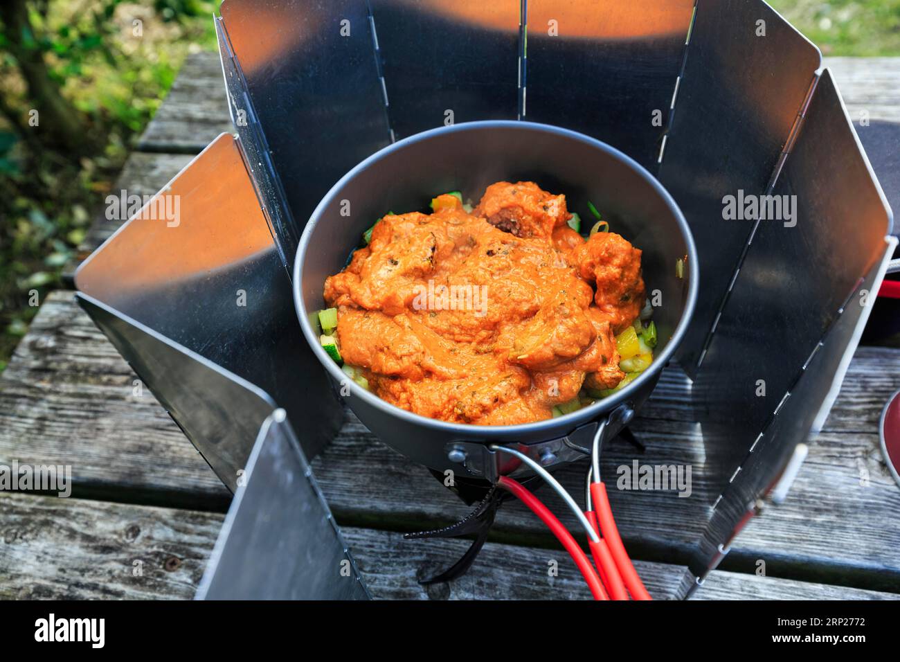 Hühnchen Tikka Masala, Fertiggerichte und frische Zutaten in einem Kochtopf, Campingkocher mit Windschutz, Gaskocher, Outdoor-Kochen, Outdoor-Kochen Stockfoto