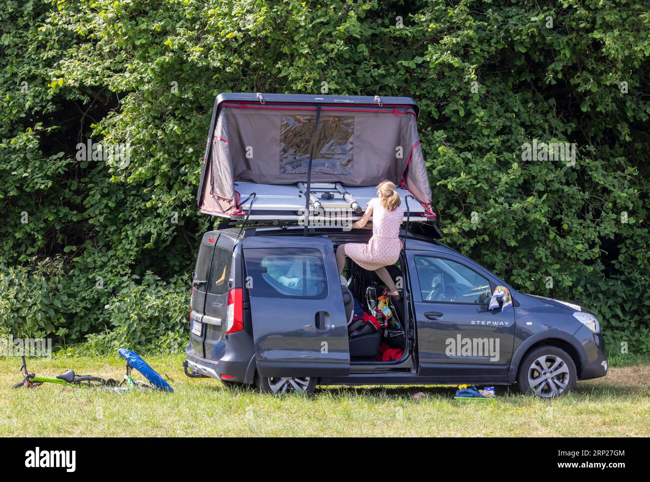 Dachzelt auf einer Dacia Stepway. Eine junge Frau kämpft um das Zelt Wunstorf, Niedersachsen, Deutschland Stockfoto