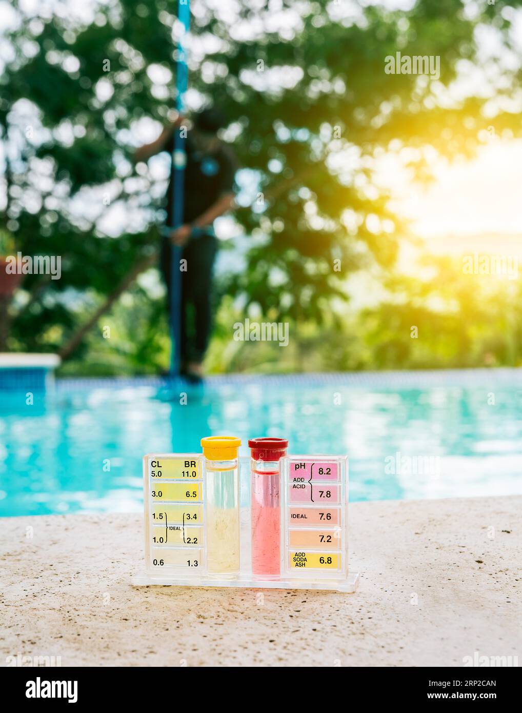 Wasser-PH-Tester-Kit am Rand des Swimmingpools mit Wartungspersonal im Hintergrund Stockfoto