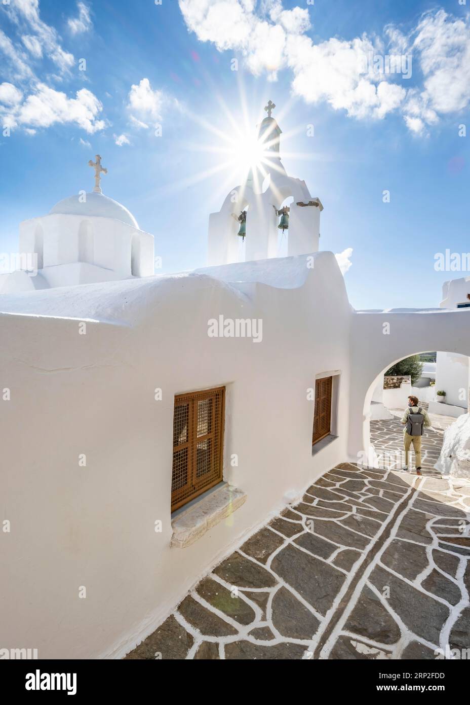 Weiße griechisch-orthodoxe Kirche mit Stern der Sonne, junger Mann in den malerischen Gassen des Dorfes Marpissa, Paros, Kykladen, Griechenland Stockfoto