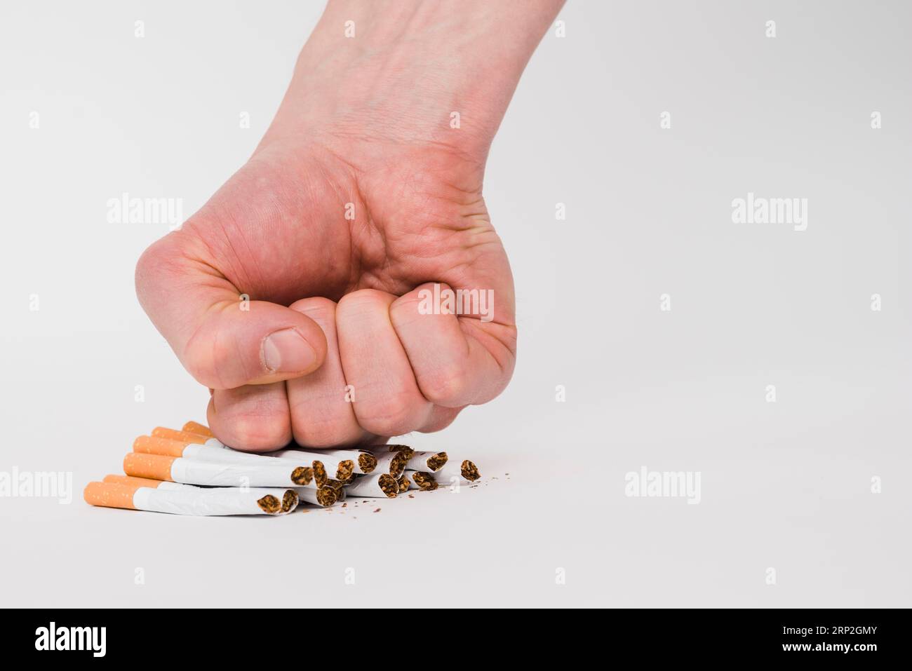 Die Menschenfäuste zerquetscht Zigaretten auf weißem Hintergrund Stockfoto