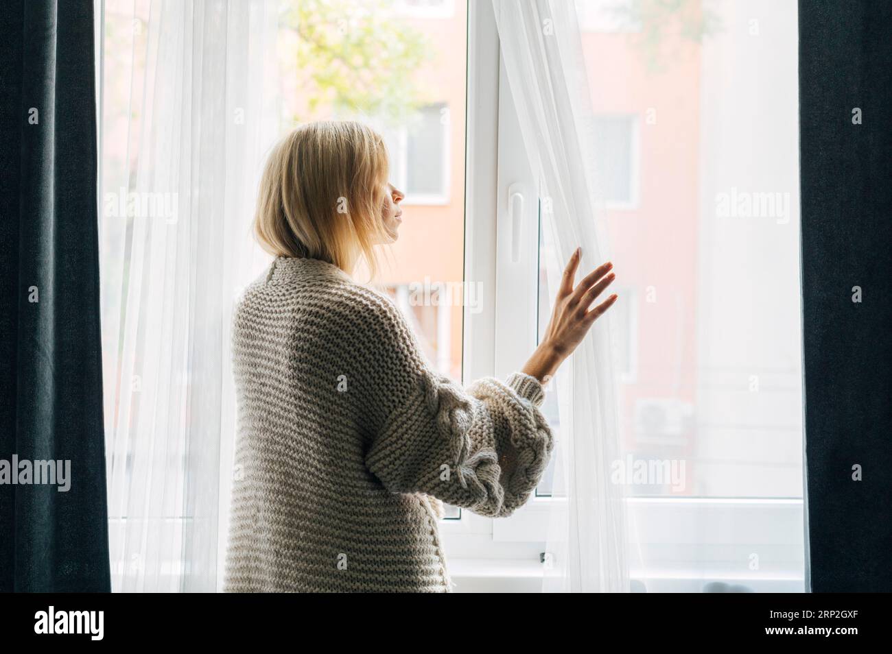 Seitenansicht melancholische Frau nach Hause während Pandemie schaut durch Fenster Stockfoto