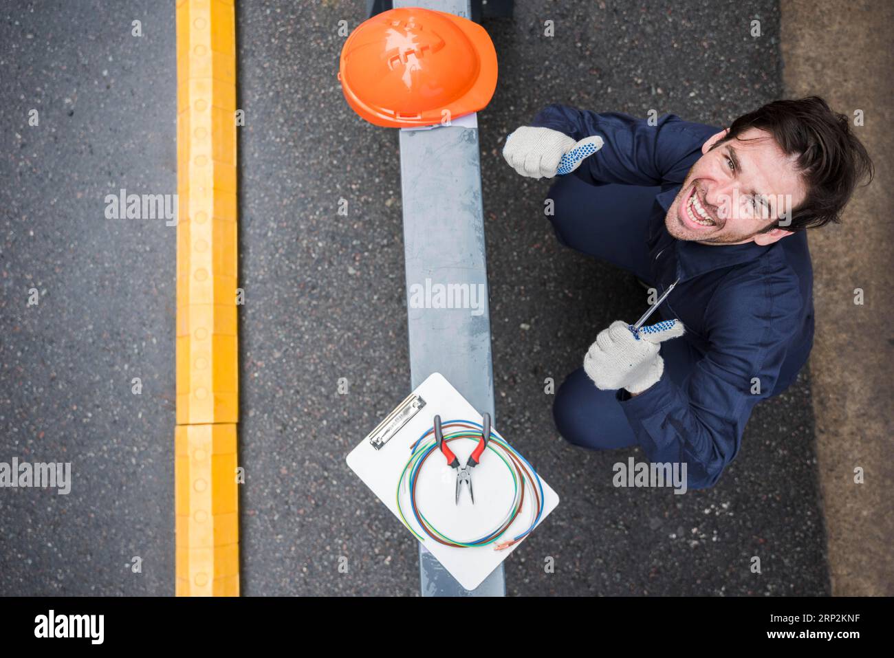 High-Angle-Ansicht glücklich männlich Elektriker zeigt Daumen nach oben Arbeitsplatz Stockfoto
