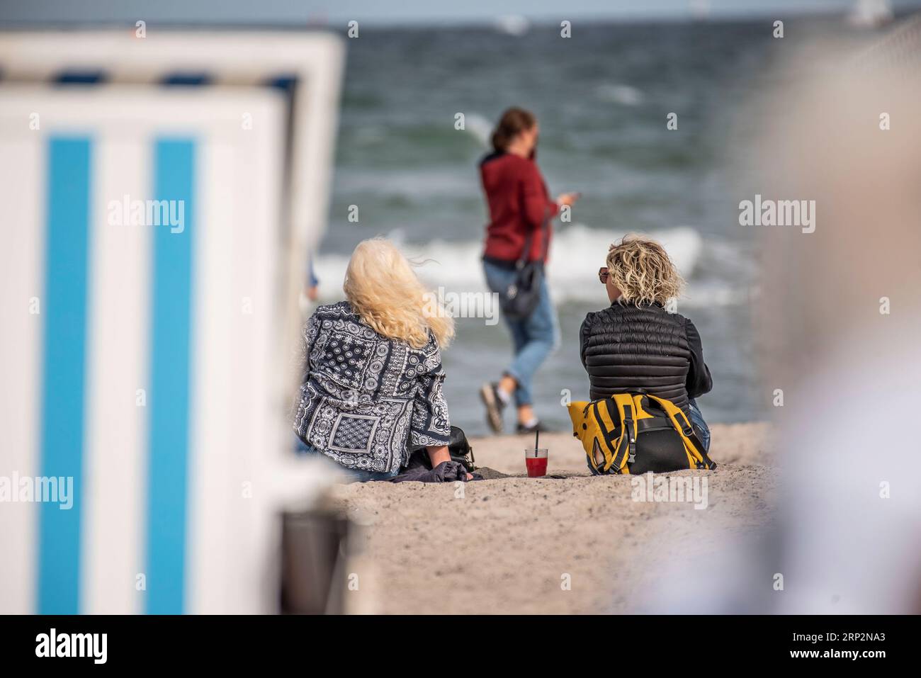 03. September 2023, Mecklenburg-Vorpommern, Rostock Warnemünde: Zwei Frauen sitzen zwischen den Liegestühlen am Ostseestrand von Warnemünde. Das erste Herbstwochenende zieht noch heute Badende in die Ostsee von Mecklenburg-Vorpommern. Die neue Woche beginnt meist sonnig und trocken. Im hohen Norden steigen die Höchsttemperaturen auf 21 bis 25 Grad, ansonsten werden meist Höchstwerte von 25 bis 31 Grad erreicht. Der Wind bläst meist schwach aus verschiedenen Richtungen, berichtet der Deutsche Wetterdienst. Foto: Frank Hormann/dpa Stockfoto