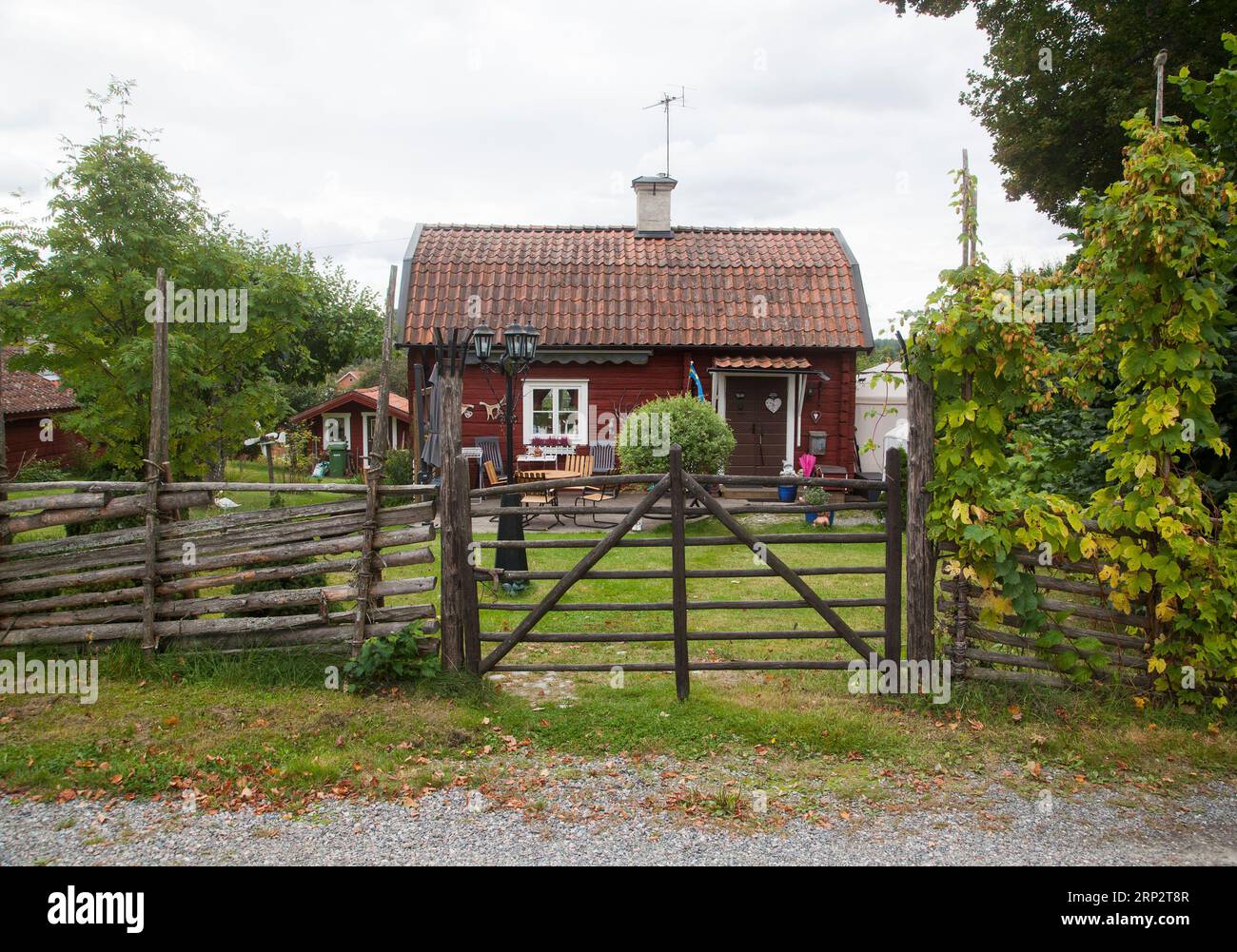 Schwedisches Sommerhaus auf dem Land mit einem Rundpfahlzaun und einem traditionellen Tor Stockfoto