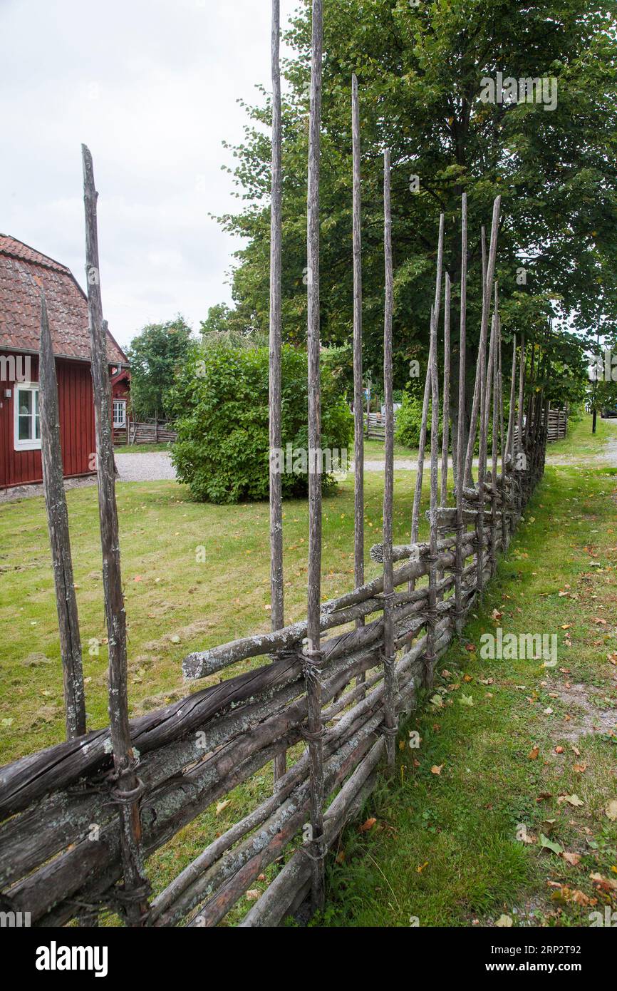 ROUNDPOLE ZAUN um kleine Hütte in Landschaft traditionelle Art der Markierung von Grundstücksgrenzen in Schweden Stockfoto