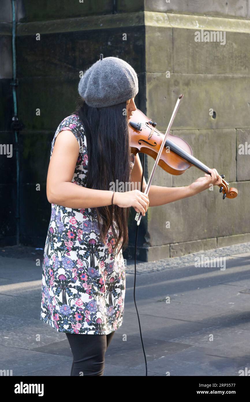 Edinburgh, Schottland, Großbritannien - 15. August 2023: Eine junge Asiatin spielt neben St. Giles Cathedral an Edinburghs Royal Mile während der Fringe Stockfoto