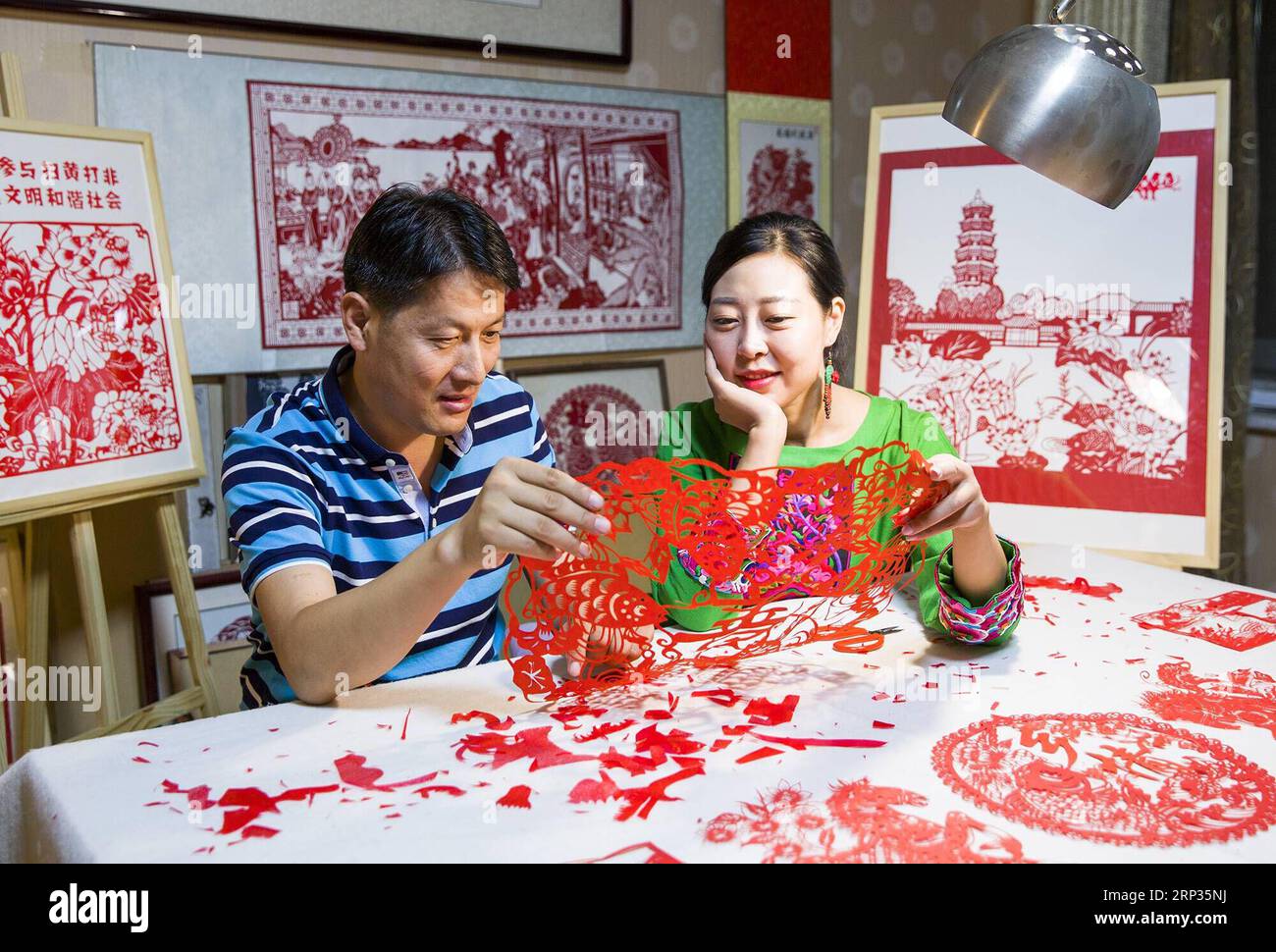 (180921) -- TENGZHOU, 21. September 2018 -- die Papierschneiderin Qiu Ting und ihr Ehemann Qiu Hanping schauen sich ein Papierschneiderei mit Erntethema zu Hause in der Stadt Tengzhou, Ostchinesische Provinz Shandong, 17. September 2018 an. Qiu verbrachte mehr als zwei Monate damit, ein 2.018 Zentimeter langes Papercutting zu kreieren, um das erste chinesische Bauernerntfest zu begrüßen, das auf die herbstliche Tagundnachtgleiche fällt, oder 23. September dieses Jahres. ) (Hxy) CHINA-TENGZHOU-PAPERCUTTING-HARVEST (CN) SongxHaicun PUBLICATIONxNOTxINxCHN Stockfoto