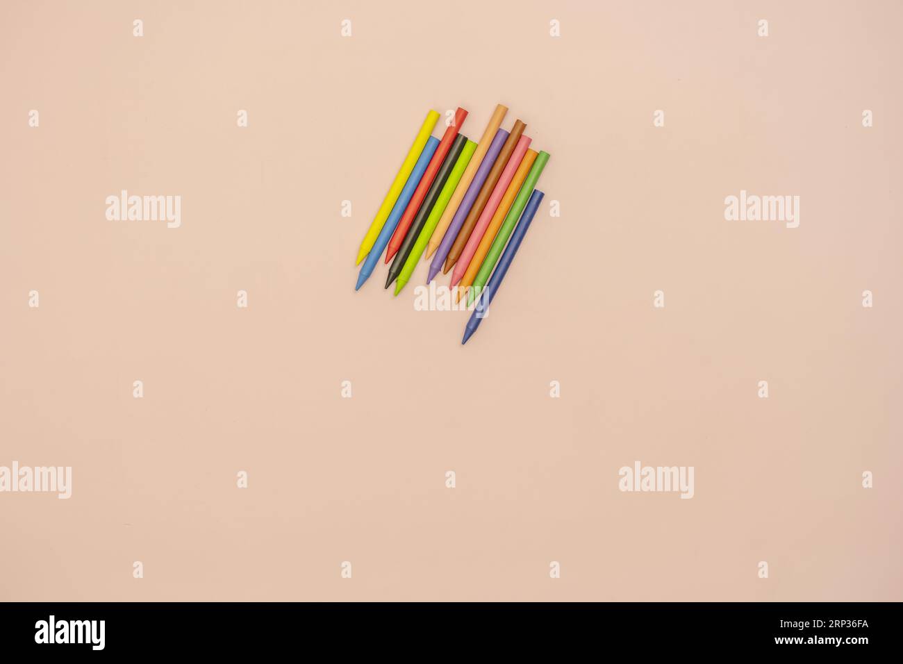 Ein Dutzend Buntstifte in verschiedenen Farben auf einer glatten rosa Oberfläche Stockfoto