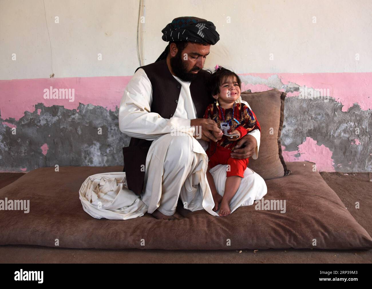 (180927) -- KANDAHAR, 27. September 2018 -- Ein Mann hält seine von Polio infizierte Tochter in der Stadt Kandahar, der Hauptstadt der Provinz Kandahar im Süden Afghanistans, 27. September 2018. In Afghanistan wurde ein neuer Fall von infektiöser Poliomyelitis entdeckt, der die Anzahl der bestätigten Fälle von Poliovirus in diesem Jahr auf 15 erhöht hat, sagte das afghanische Gesundheitsministerium am Mittwoch. )(zhf) AFGHANISTAN-KANDAHAR-NEW POLIO CASE SanaullahxSeiam PUBLICATIONxNOTxINxCHN Stockfoto