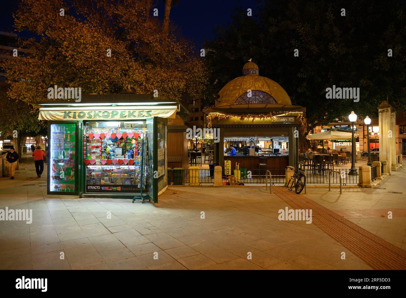 Alicante, Spanien, beleuchtete kleine Unternehmen in einem öffentlichen Park. Links ein Kioskopekes und rechts eine Bar oder ein Trinklokal. Stockfoto