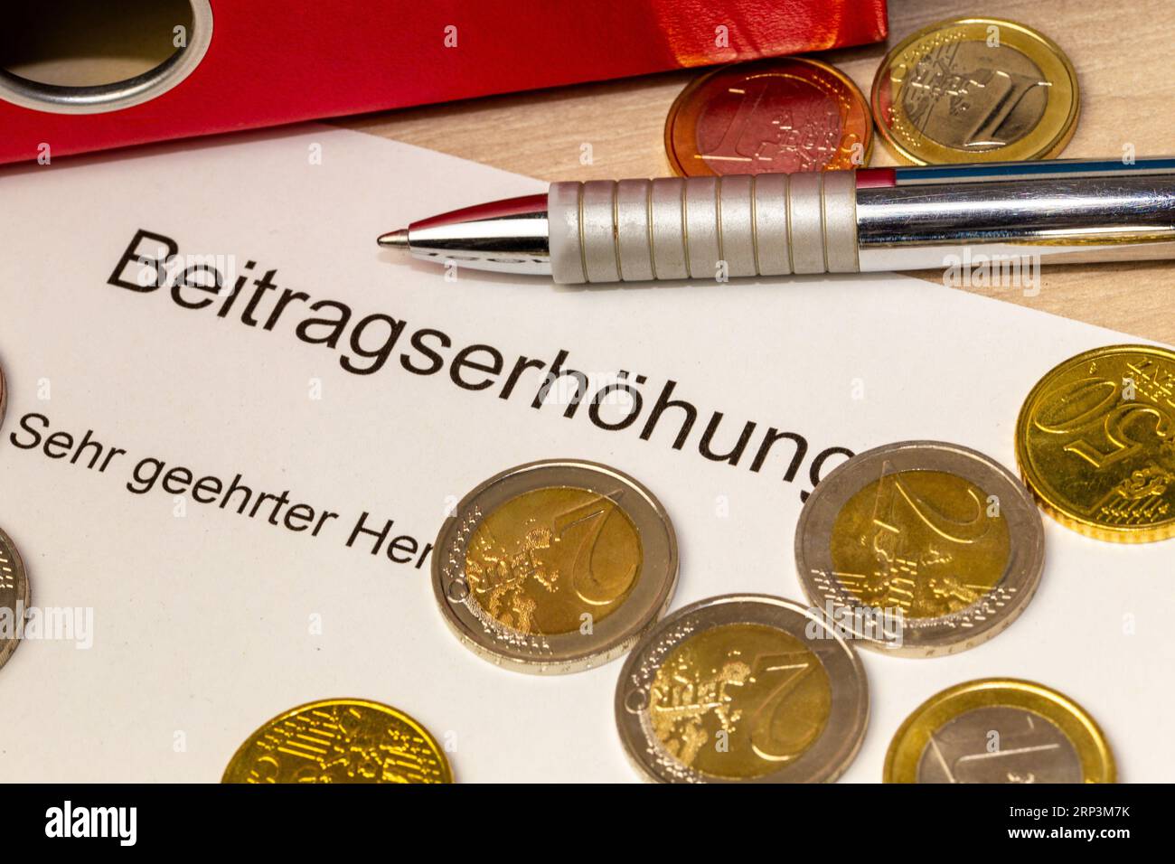 Symbolbild der Beitragssteigerung (Deutschland): Brief, Euro-Münzen, Biros und Mappe Stockfoto